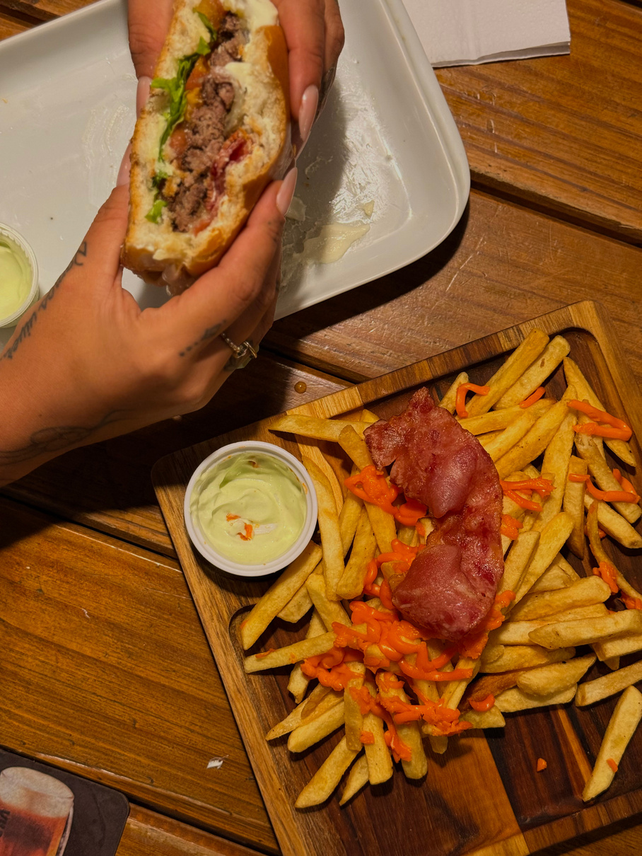 Hambúrguer cortado e porção de batatas com acompanhamentos do Litoral Burguer